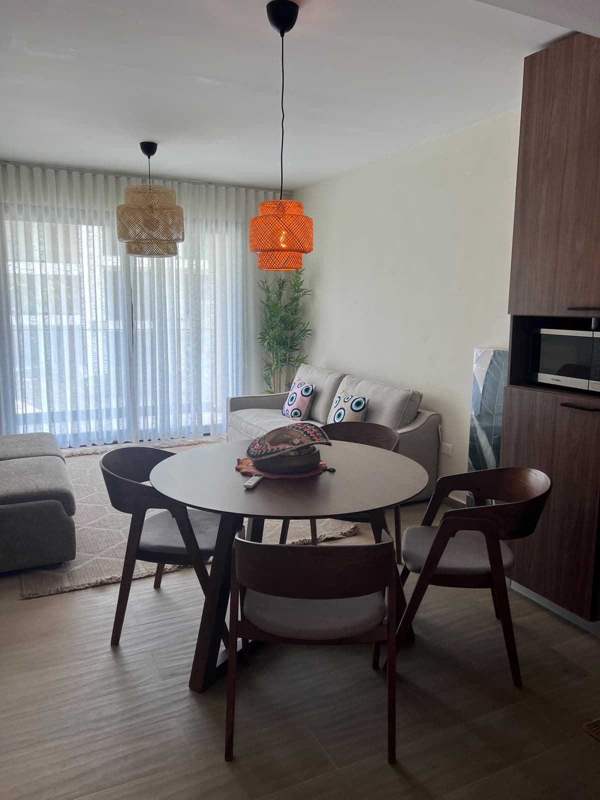 Dining area laid out beside sheer curtains and a kitchen in a Dominican condo