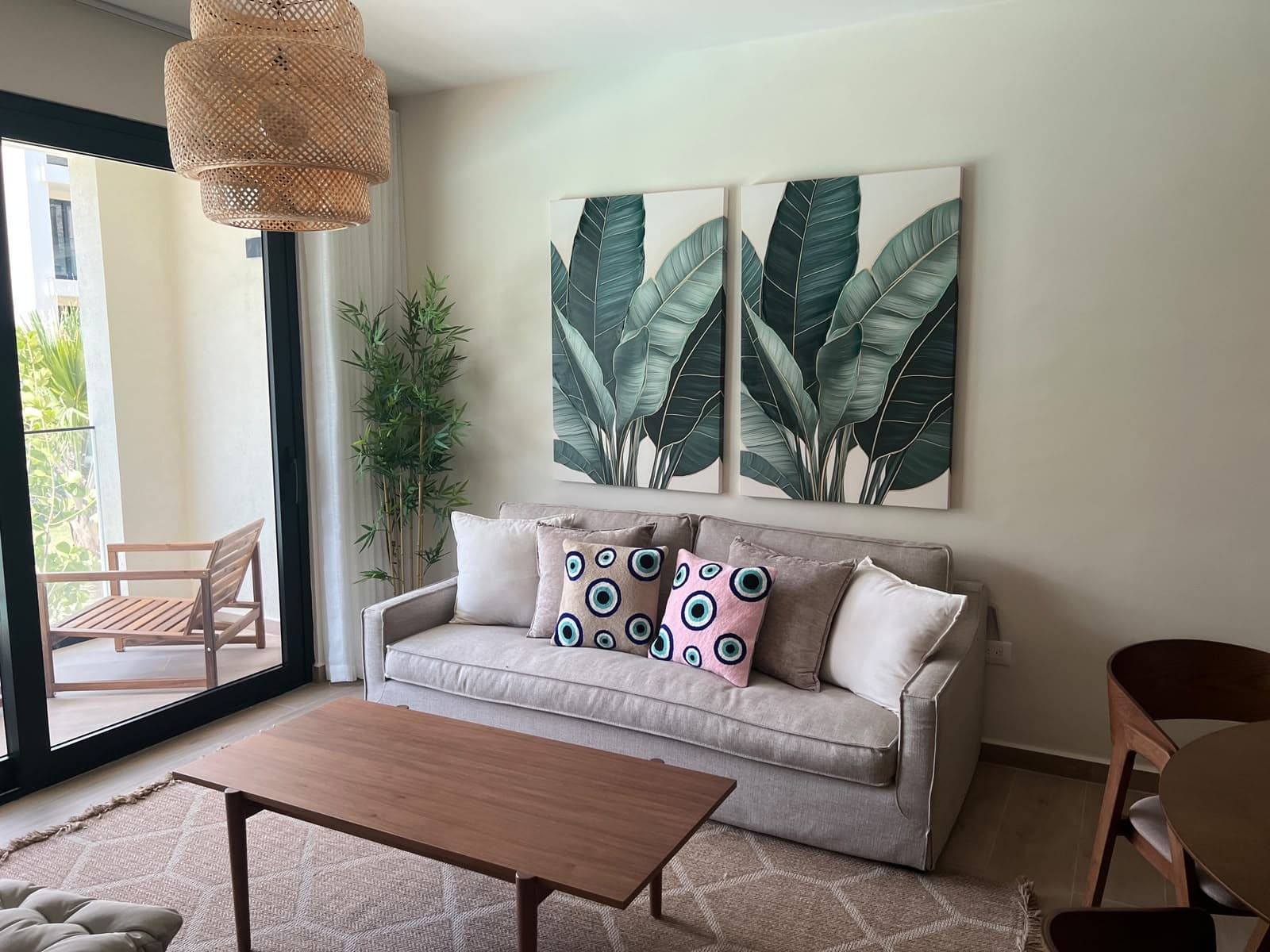 Finished living room with linen sofa, botanical art, rattan lighting, and balcony seating