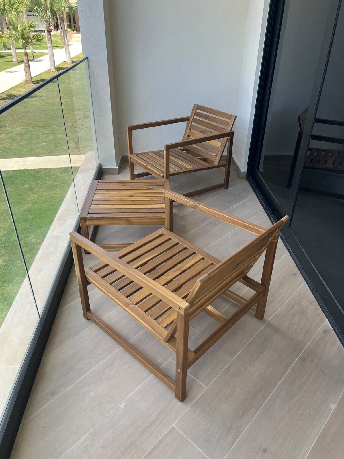 Teak lounge chairs and a table set on a balcony after delivery